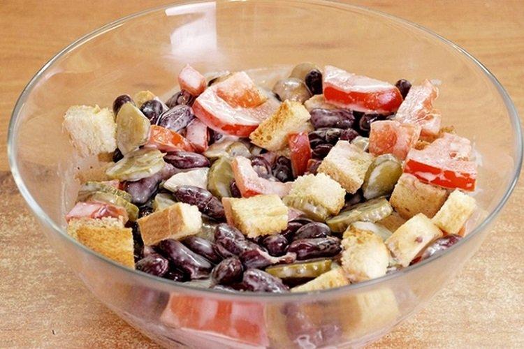 Salat aus Croutons, eingelegten Pilzen, Tomaten und roten Bohnen