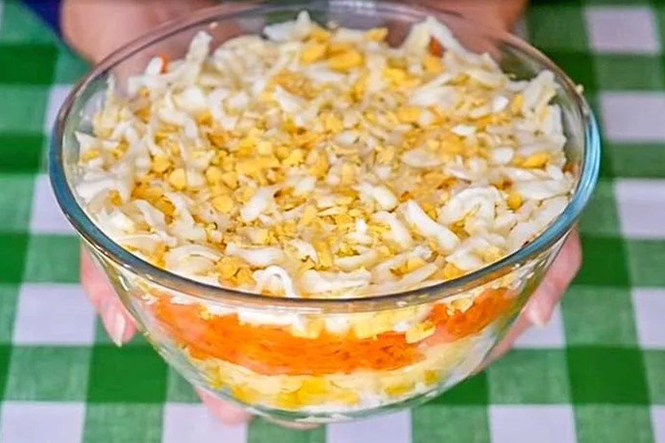 Schichtsalat mit Krabbenfleisch, Eiern, Mais und koreanischen Karotten