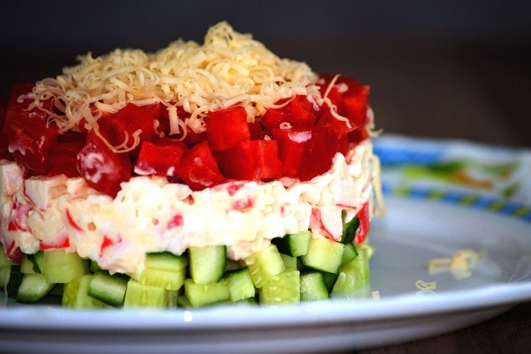 Schichtsalat aus Käse, Krabbenfleisch und frischem Gemüse
