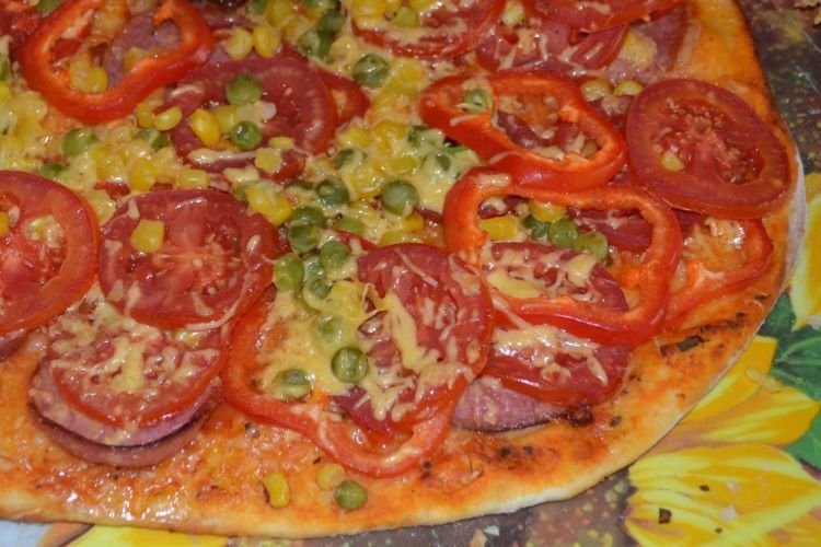 Pizza mit Wurst und grünen Erbsen