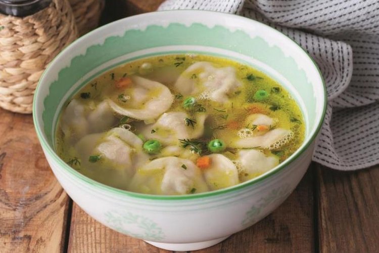 Sopa con dumplings, guisantes verdes y zanahoria