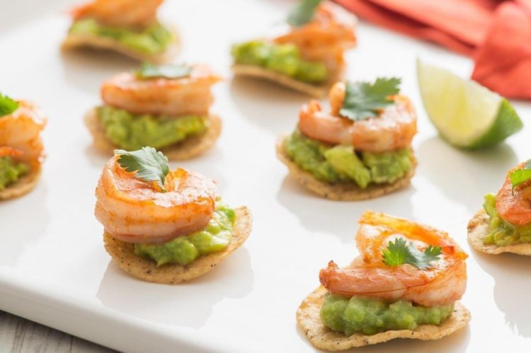 Aperitivo con camarones y aguacate sobre patatas fritas