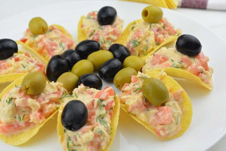 Aperitivo con tomates y aceitunas sobre patatas fritas