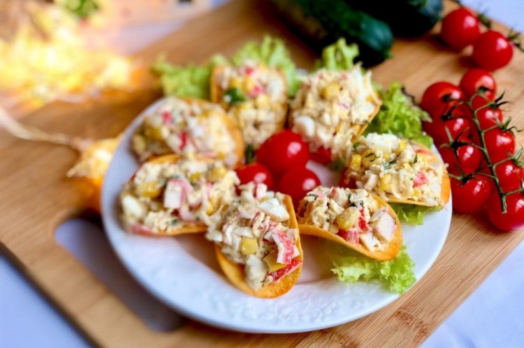Aperitivo con palitos de cangrejo y maíz sobre patatas fritas
