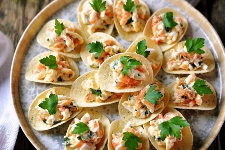 Aperitivo con queso crema y salmón sobre patatas fritas