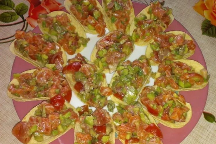 Aperitivo con pescado rojo y aguacate sobre patatas fritas