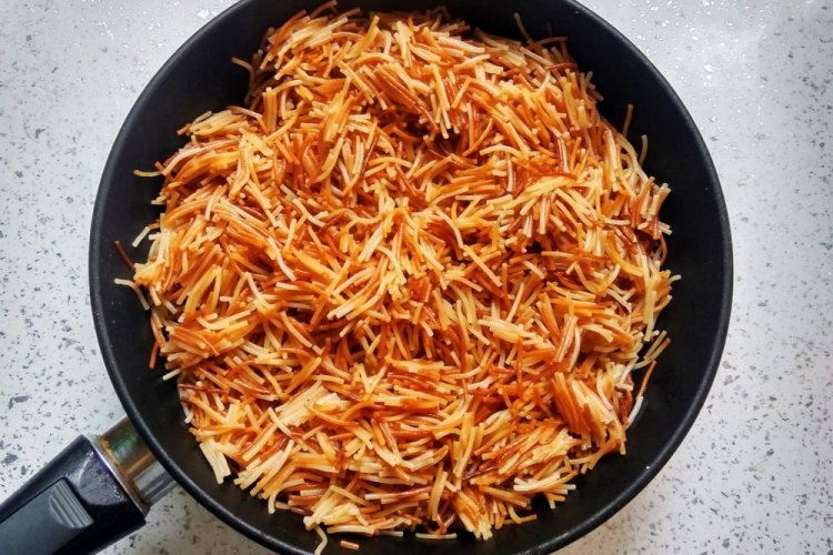 Fideos fritos con cebolla en sartén