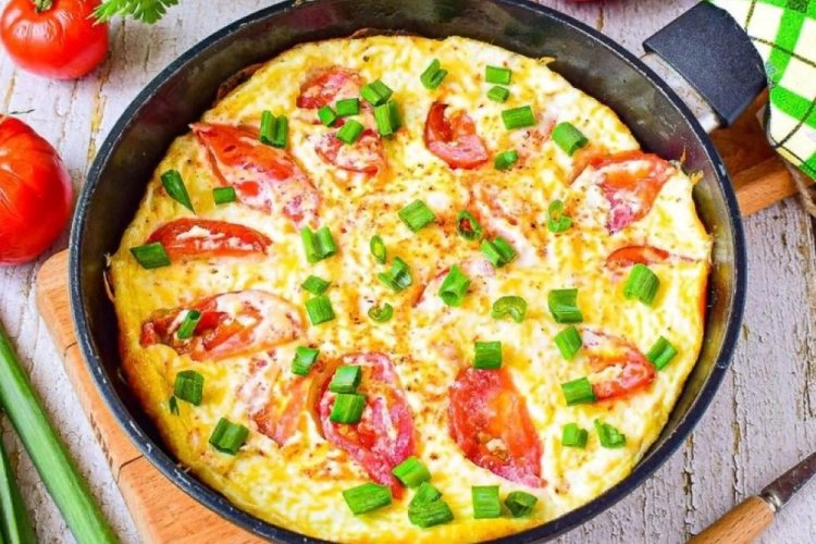 Tortilla con tallos de ajo y tomates bajo queso