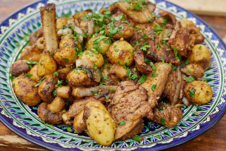 Patatas con carne y cebolla en un caldero a la lumbre