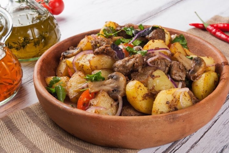 Patatas con carne y champiñones en un caldero a la lumbre