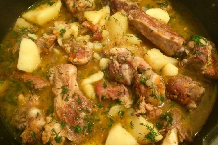 Patatas con carne y tocino en un caldero a la lumbre