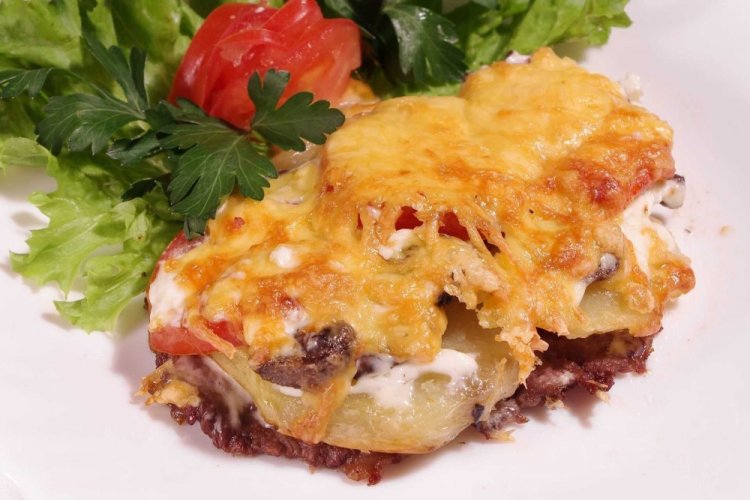 Potatoes with Mushrooms and Meat on a Baking Sheet in the Oven